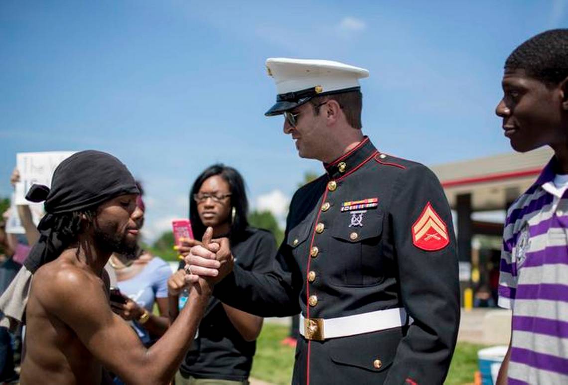 Tyson Manker in Marine Corps dress blues clasping hands with a demonstrator during the 2014 protests in Ferguson, Missouri
